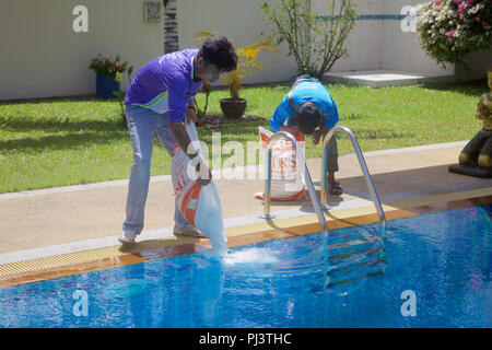 Bags of salt being poured into a salt water swimming pool in Thailand Stock Photo