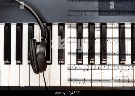 An overhead photo of piano keys with headphones and sheet music Stock Photo