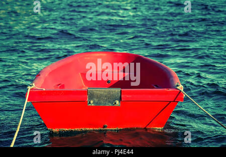 Small wooden  bright red dingy morred in marina. Stock Image. Stock Photo