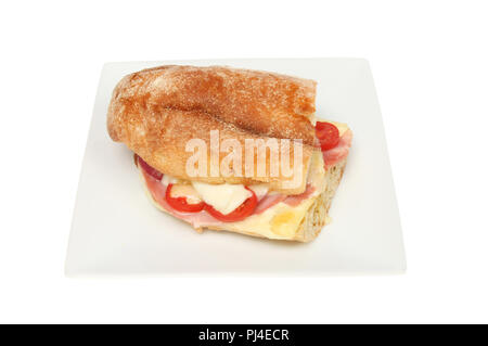 Toasted cheese, ham, tomato and red onion in a chiabatta roll on a plate isolated against white Stock Photo