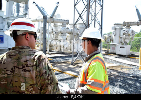 249th Engineer Battalion (Prime Power) is a U.S. Army unit focused on electrical engineering and power support. The archival photographic print records personnel discussing operations at a power sub-station near La Plata Lake Dam, Toa Alta, Puerto Rico, in August 2018 during Hurricane Maria recovery efforts. The historical record captures technical evaluation and coordination with local utility authorities. Stock Photo