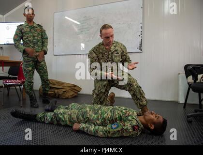 Hospital Corpsman 3rd Class Tom McCarthy, from McKinleyville, California, assigned to Naval Hospital Yokosuka, and members of the Timor-Leste Defense Force simulate checking for bleeding on a patient during CARAT Timor-Leste 2018 at Hera Naval Base, Aug. 29, 2018. CARAT Timor-Leste 2018 is designed to address shared maritime security concerns, build relationships and enhance interoperability among participating forces. (U.S. Navy photo by Mass Communication Specialist 3rd Class Danny Ray Nuñez Jr./Released) Stock Photo