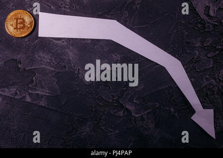 Golden Bitcoin Crypto currency coin on a dark background plot of the currency price drop in the market Stock Photo