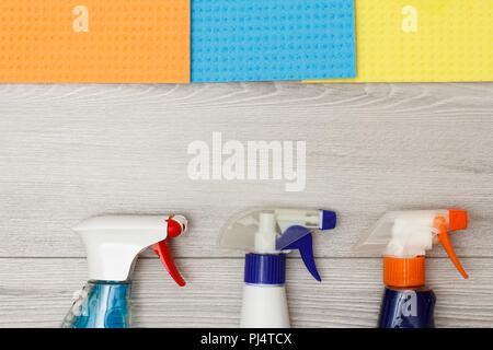 Bottles of detergent and color microfiber napkins for cleaning on grey wooden background with copy space in the center. Set of cleaning tools and equi Stock Photo