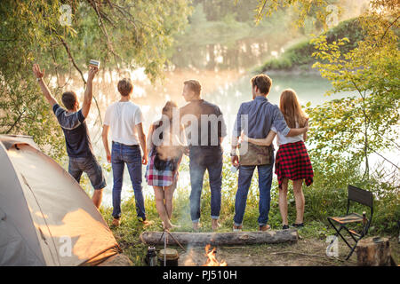young cheerful people are standing against the sunset . Travel concept Stock Photo