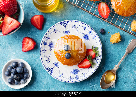 Muffin, cupcake with fresh berries on a plate. Blue background. Top view. Stock Photo
