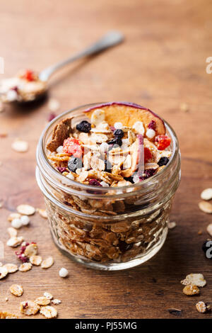 Granola, muesli in glass jar. Healthy breakfast. Organic oats with apples, berries, nuts. Copy space Stock Photo