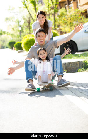 Happy young family playing with skateboard Stock Photo