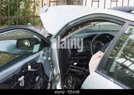 Destroyed interior at driver seat of a car crashed into a fenced wall. Overhead shot from behind Stock Photo
