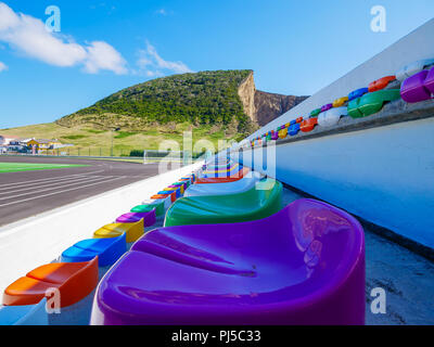 Several rows of colorful seats in a stadion during daytime Stock Photo