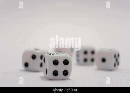 A close up of five white dice focused on the number four side of one dice. Numbers two, one, five and six are also visible in the image Stock Photo