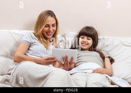 Mother and daughter using digital tablet in bed Stock Photo
