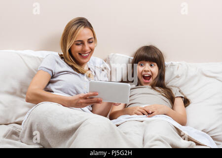 Mother and daughter using digital tablet in bed Stock Photo