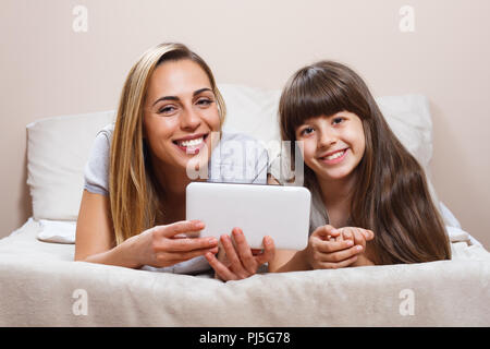 Mother and daughter using digital tablet in bed Stock Photo