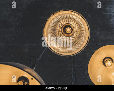 A group of hanging lights or ceiling lamps on cement texture background in loft style cafe. Stock Photo