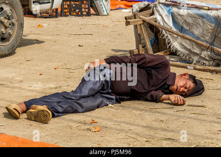 Dong Van, Vietnam - March 18, 2018: Drunk man lying on the floor at Dong Van sunday market Stock Photo