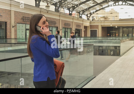 A beautiful girl walking the shopping center and talking on the phone Stock Photo
