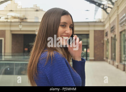 Portrait of a beautiful girl talking on the phone, walking shopping mall Stock Photo