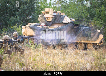 U.S. Army Soldiers assigned to 2nd Battalion, 5th Cavalry Regiment, 1st Armored Brigade Combat Team, 1st Cavalry Division, fire small arms weapons beside an M2A3 Bradley Fighting Vehicle during a Table XII live fire exercise, Novo Selo Training Area, Bulgaria, August 24, 2018. This exercise is in support of Atlantic Resolve, an enduring training exercise between NATO and U.S. Forces. (U.S. Army National Guard photo by Sgt. Jamar Marcel Pugh, 382nd Public Affairs Detachment/ 1st ABCT, 1st CD/Released) Stock Photo