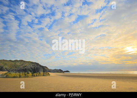 Empty, sandy beach view, Ynys LLanddwyn, Wales with dramatic, wispy cirrus clouds in blue sky as summer sun is setting. Stock Photo