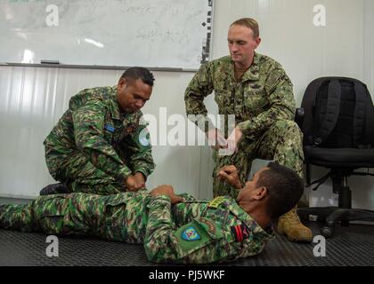 Hospital Corpsman 3rd Class Tom McCarthy, from McKinleyville, California, assigned to Naval Hospital Yokosuka, and members of the Timor-Leste Defense Force apply a tourniquet during CARAT Timor-Leste 2018 at Hera Naval Base, Aug. 28, 2018. CARAT Timor-Leste 2018 is designed to address shared maritime security concerns, build relationships and enhance interoperability among participating forces. (U.S. Navy photo by Mass Communication Specialist 3rd Class Danny Ray Nuñez Jr./Released) Stock Photo
