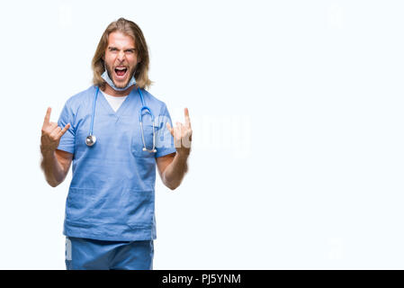 Young handsome doctor man with long hair over isolated background shouting with crazy expression doing rock symbol with hands up. Music star. Heavy co Stock Photo
