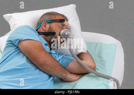 APNEA. Man with sleeping apnea and CPAP machine Stock Photo