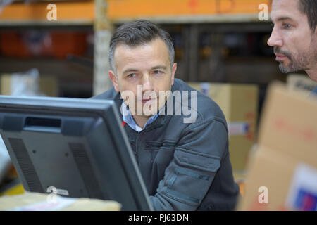 warehouse worker and manager using computer in a warehouse Stock Photo