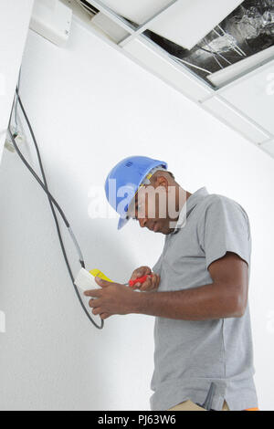 male technician holding clipboard while examining wire Stock Photo