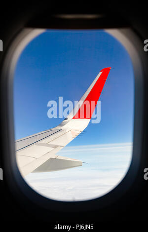 Airliner wing as seen through window of flying airplane Stock Photo