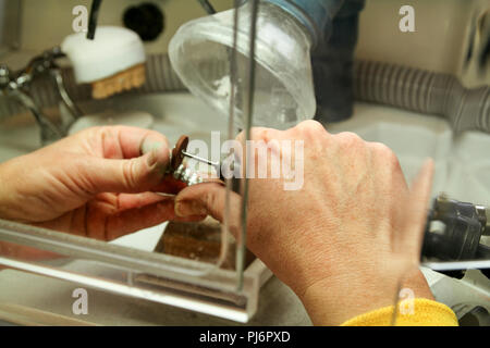 Dentures and dentistry. Dental prosthesis, dentures, prosthetics work. Dental technician in pricess of making dentures. Hands of dental technician. Stock Photo