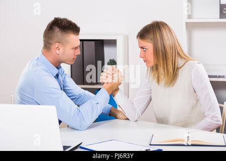 Arm wrestling between businessman and businesswoman at work. Stock Photo