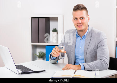 Businessman is drinking water and working in his office. Stock Photo