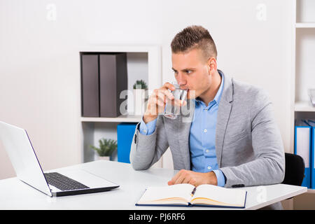 Businessman is drinking water and working in his office. Stock Photo