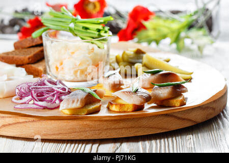 Sandwich on fried potatoes with herring, green onion. Tasty appetizer with sauerkraut, pickled cucumber, mustard on wooden Board. Rye bread and lard Stock Photo