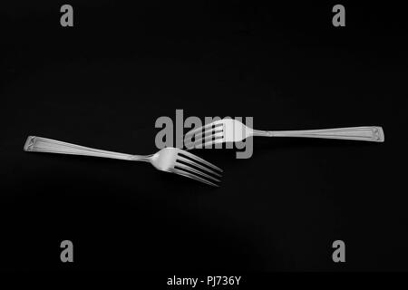 Two forks in on the black background in the studio. Stock Photo