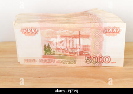 Big stack of Russian money banknotes of five thousand rubles lying on a wooden table Stock Photo