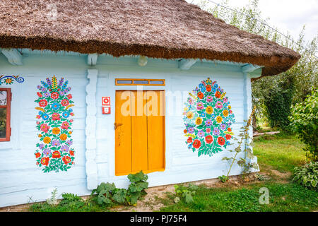 Zalipie, Poland, August 19, 2018:  Colourful house with flowers painted on walls and sundial in the village of Zalipie, Poland. It is known for a loca Stock Photo