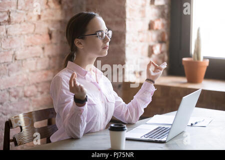 Young woman doing meditation in office at work Stock Photo