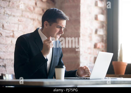Frustrated man looking at laptop screen at workplace Stock Photo