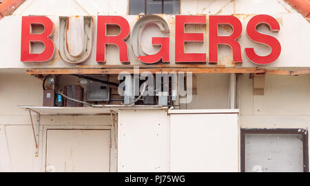 Retro red burger sign from the 60s in disrepair, rusty gray electrical boxes and conduit below sign, white background from the 60s Stock Photo