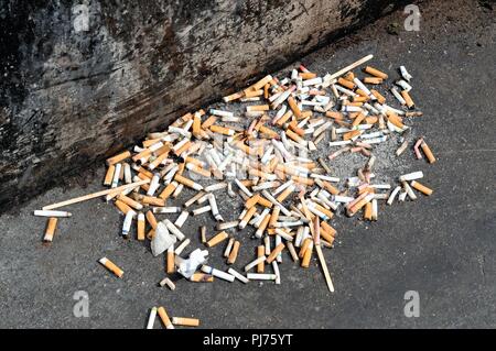 Close up of a pile of discarded cigarette butts on a pavement in London UK Stock Photo