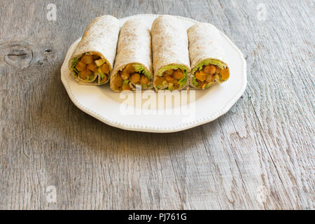 Four vegetarian tortillas with chickpeas, butternut squash, spring onion, cucumber, avocado on the dark wooden table, copy space for text Stock Photo