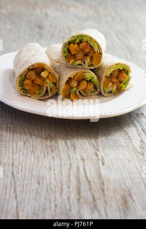Vertical photo of four vegetarian tortillas with chickpeas, butternut squash, spring onion, cucumber, avocado on the dark wooden table, copy space for Stock Photo