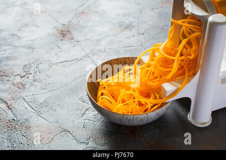 Spiralized butternut squash with spirazlizer on the grey stone background, selective focus, copy space for text Stock Photo