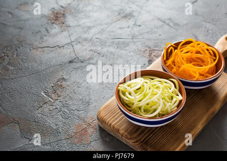 Spiralized butternut squash and courgette, zucchini on the grey stone background, selective focus, copy space for text Stock Photo