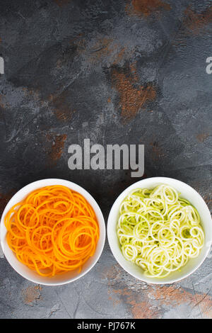 Zucchini and butternut squash spiraled pasta on the grey stone background, selective focus, copy space for text Stock Photo
