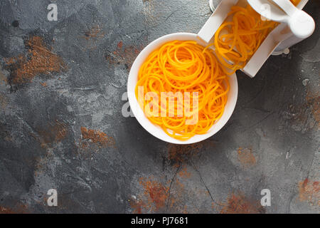 Top view of spiralized butternut squash with spirazlizer on the grey stone background, selective focus, copy space for text Stock Photo
