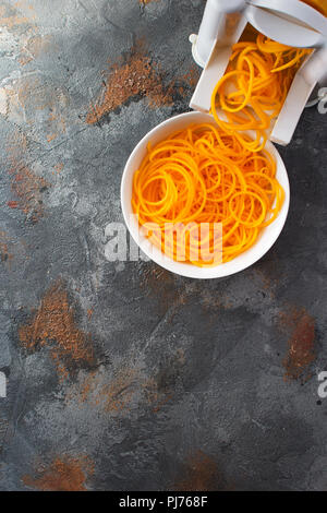 Spiralized butternut squash with spirazlizer on the grey stone background, selective focus, top view, vertical, copy space for text Stock Photo