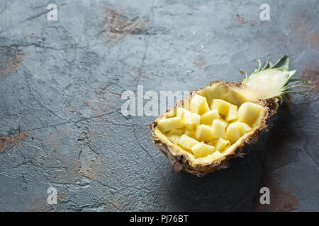 Pineapple halved and chopped, on the dark grey stone background, copy space, selective focus Stock Photo